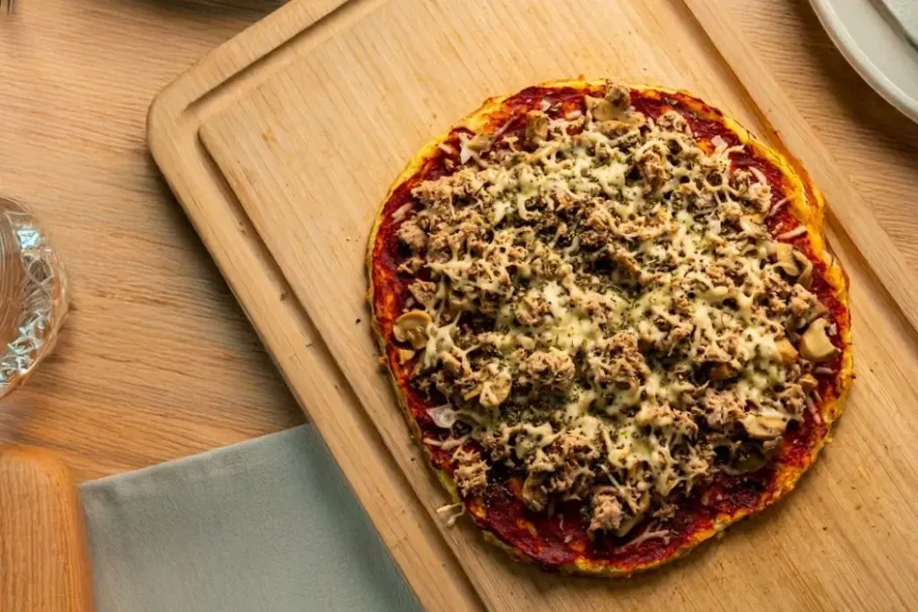 Ketopizza aseteltuna leikkuulaudalle.